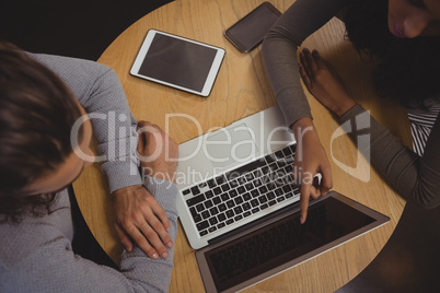 Woman with friend pointing at laptop