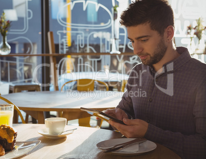 Businessman using tablet while having breakfast in cafe