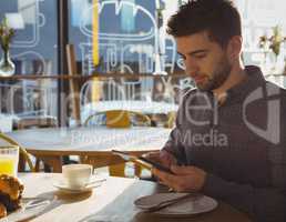 Businessman using tablet while having breakfast in cafe