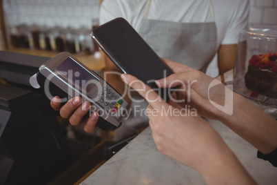 Cropped hand of customer making contactless payment with waiter holding credit card reader