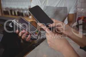 Cropped hand of customer making contactless payment with waiter holding credit card reader