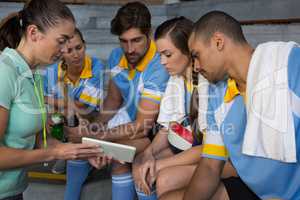 Coach discussing over digital tablet with volleyball players