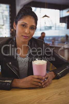 Portrait of woman with milkshake glass in cafe