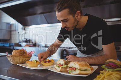 Waiter arranging food in plate at cafe