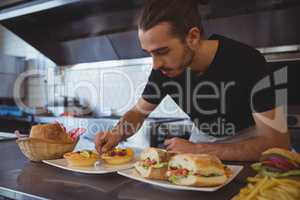 Waiter arranging food in plate at cafe