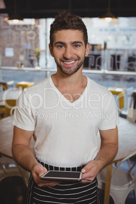 Portrait of waiter holding digital tablet