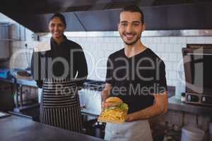Portrait of waiter with coworker holding food tray in cafe