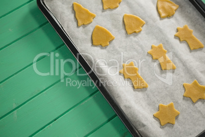 High angle view of various shape raw cookies in baking sheet