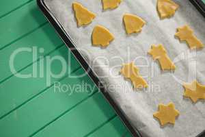 High angle view of various shape raw cookies in baking sheet