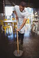 Waiter mopping floor in cafe