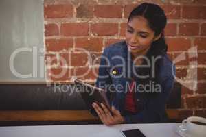 Woman using tablet against wall in cafe