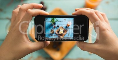 Hands taking photo of breakfast with mobile phone