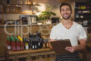 Portrait of waiter holding clipboard at cafe