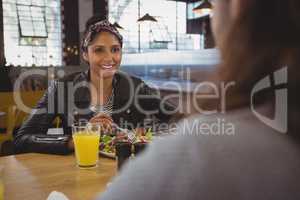 Woman with friend having salad in cafe
