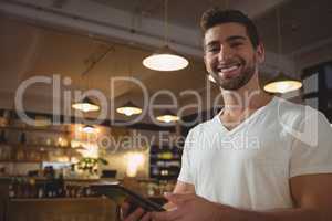 Portrait of smiling waiter using tablet in cafe