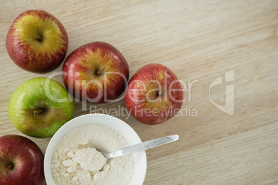 Overhead view of flour in bowl by apples