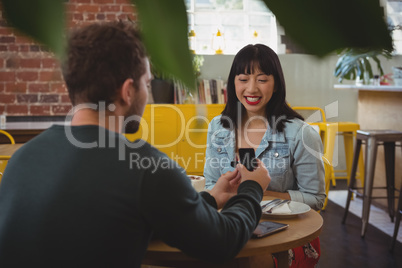 Young man gifting ring to girlfriend in cafe