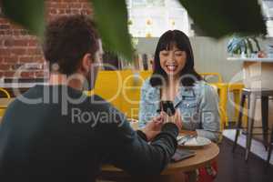 Young man gifting ring to girlfriend in cafe