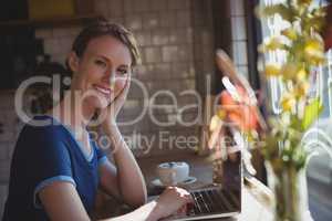 Portrait of woman using laptop at window sill