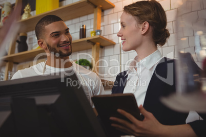 Owner with waiter holding tablet in cafe
