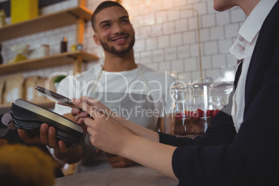 Waiter showing credit card reader to owner in cafe