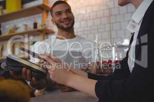 Waiter showing credit card reader to owner in cafe