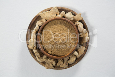 Directly above view of powder in bowl amidst dried gingers