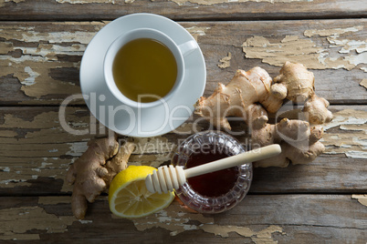 Overhead view of fresh honey and lemon with ginger tea on weathered table