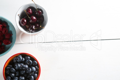 Overhead view of cherries and berries in bowls