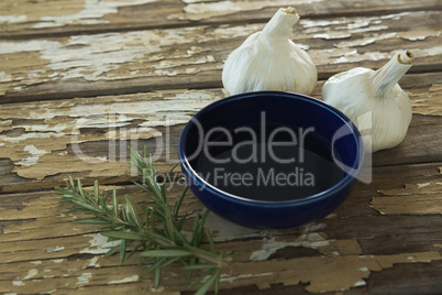 Garlic bulbs, rosemary and oil on wooden table