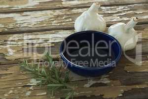 Garlic bulbs, rosemary and oil on wooden table