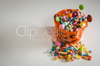Bucket with various sweet food on white background during Halloween