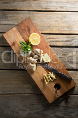 Overhead view of lemon with ginger on cutting board over table