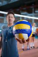 Coach holding volleyball in the court