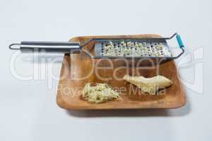 Close up of steel grater and fresh ginger on wooden plate