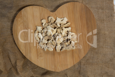 Overhead view of dried gingers on heart shape serving board over burlap