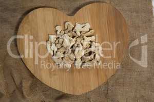 Overhead view of dried gingers on heart shape serving board over burlap