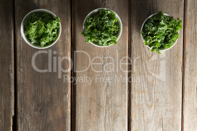 Overhead view of kale arranged side by side in bowls on table