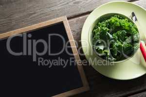 High angle view of kale in bowl on plate by blackboard