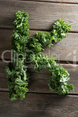 Letter K made with fresh kale leaves on wooden table