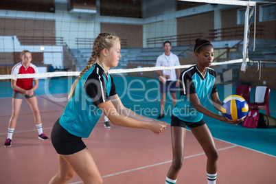 Female players playing volleyball in the court