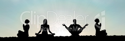 yoga group silhouette at sunset praying