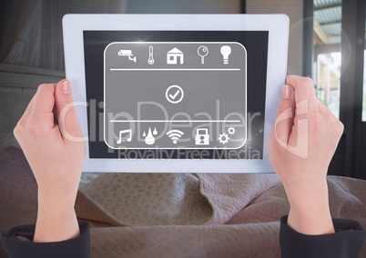 Hand holding tablet with smart home interface at home