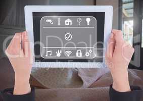 Hand holding tablet with smart home interface at home