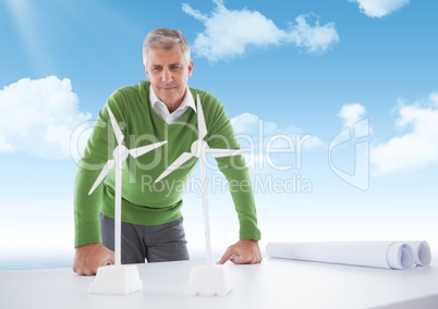 Confident business man  looking at  models of windmills on the table