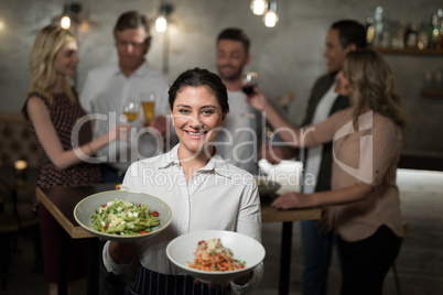 Portrait of smiling waitress holding food in bowl