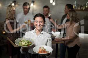 Portrait of smiling waitress holding food in bowl