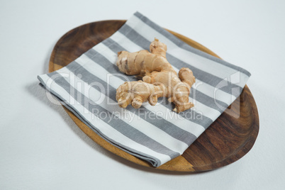 Close up of fresh ginger on striped napkin in wooden plate