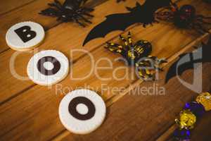 Cookies with boo text by decorations on wooden table