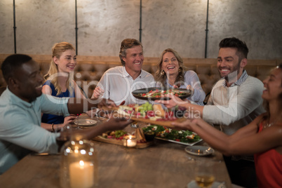 Friends passing food to each other while dining